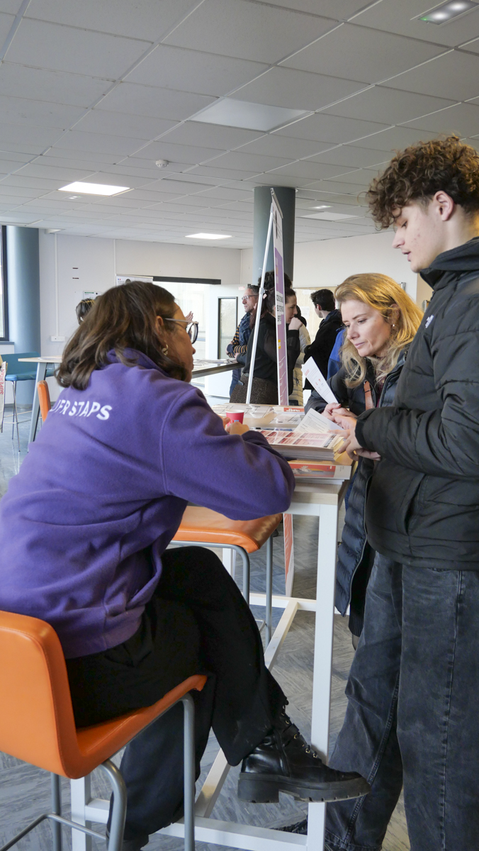 Une enseignante de STAPS renseignant un lycéen accompagné d'une personne de son entourage